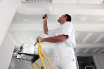 Priming the ceiling before painting it with water-based paint